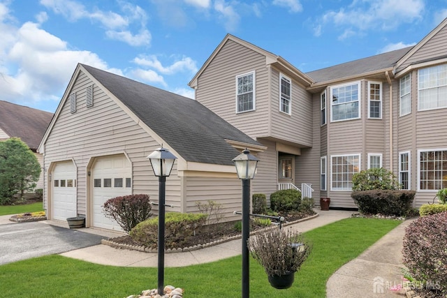 townhome / multi-family property with a garage, aphalt driveway, a shingled roof, and a front yard