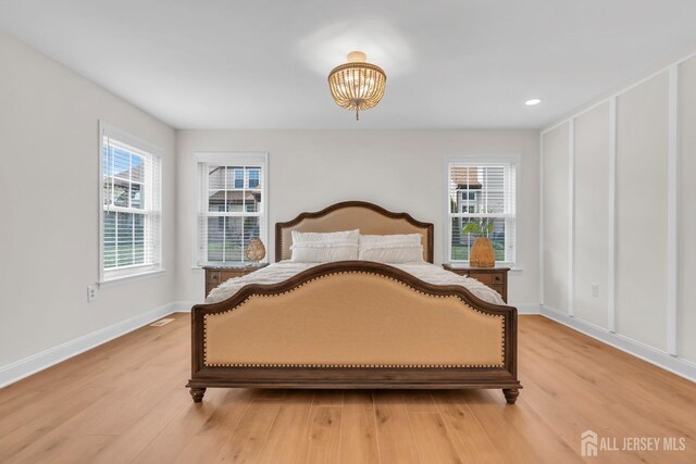 bedroom with an inviting chandelier, light wood-style floors, recessed lighting, and baseboards