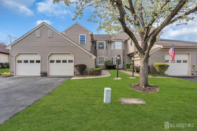 traditional-style house featuring a front lawn, driveway, and a garage