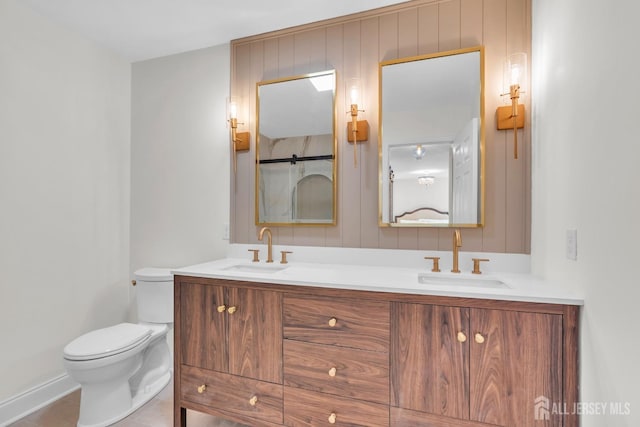 bathroom featuring tile patterned floors, toilet, double vanity, and a sink