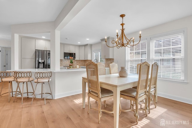 dining room featuring baseboards, recessed lighting, an inviting chandelier, and light wood finished floors