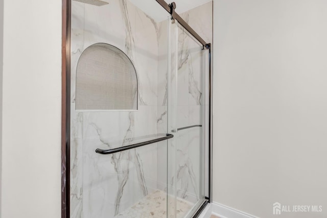 bathroom with a marble finish shower and baseboards