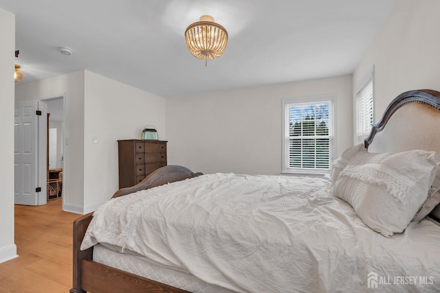 bedroom featuring baseboards, a notable chandelier, and light wood-style floors
