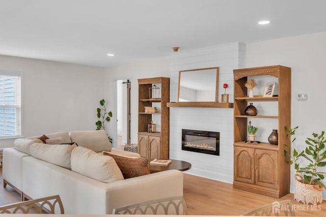 living area with a fireplace, recessed lighting, baseboards, and light wood-style floors