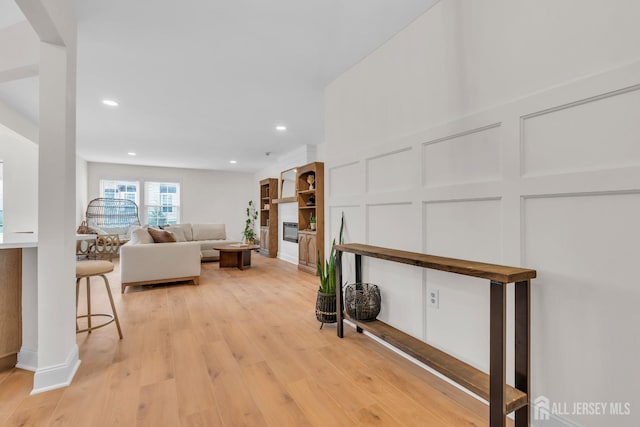 living room with a decorative wall, light wood-type flooring, and recessed lighting