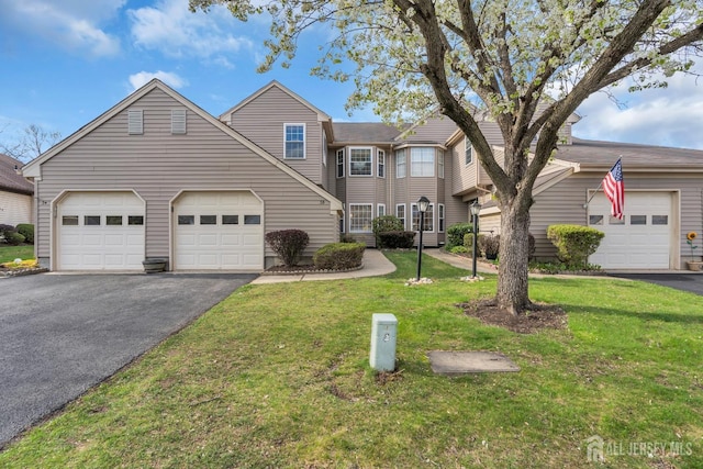 traditional home featuring a front lawn, a garage, and aphalt driveway