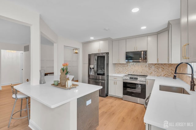 kitchen with a sink, light wood-style flooring, stainless steel appliances, and light countertops