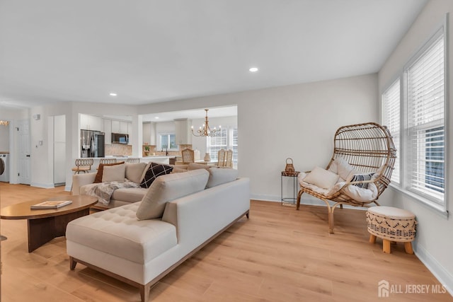 living room with recessed lighting, an inviting chandelier, light wood-style flooring, and baseboards