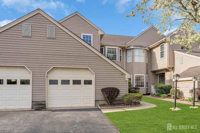 view of front of home with a garage, aphalt driveway, and a front yard