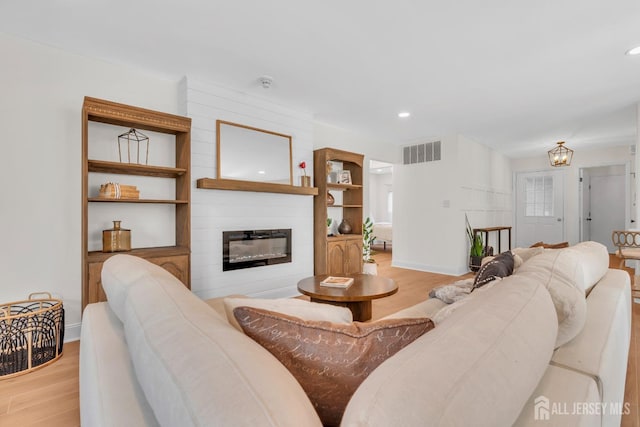 living room with recessed lighting, a large fireplace, light wood-type flooring, visible vents, and baseboards