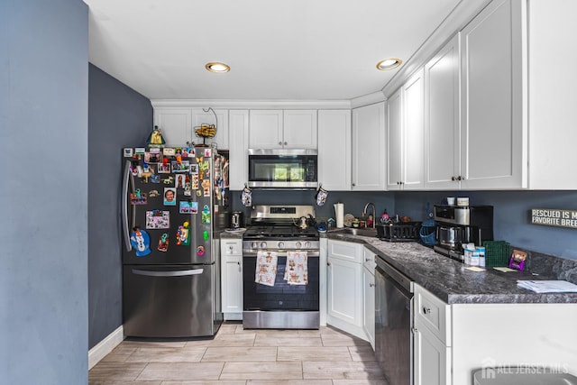 76 Woodland Dr, Keyport, NJ 07735 - kitchen featuring appliances with stainless steel finishes, a sink, white cabinetry, dark countertops, and wood tiled floors