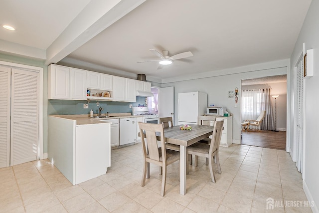 kitchen featuring light countertops, a ceiling fan, white cabinets, a sink, and white appliances