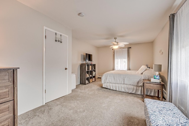 bedroom with carpet floors, a baseboard heating unit, and a ceiling fan