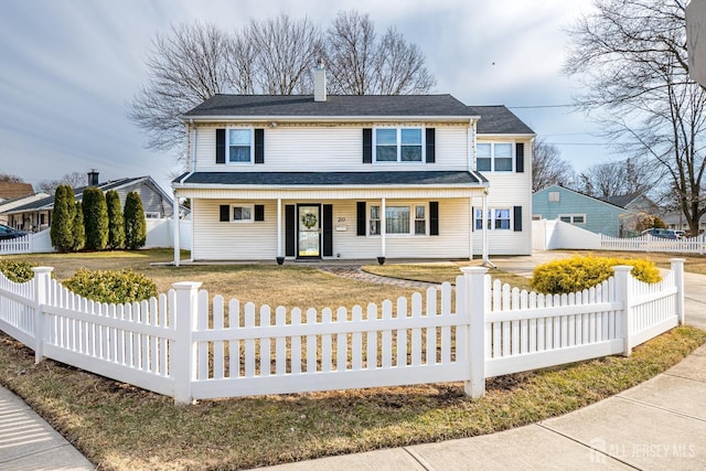 traditional-style home featuring a porch, a chimney, and a fenced front yard