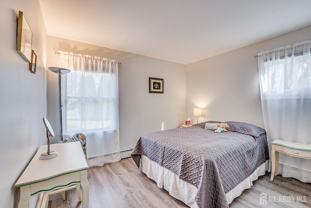 bedroom featuring a baseboard heating unit and wood finished floors