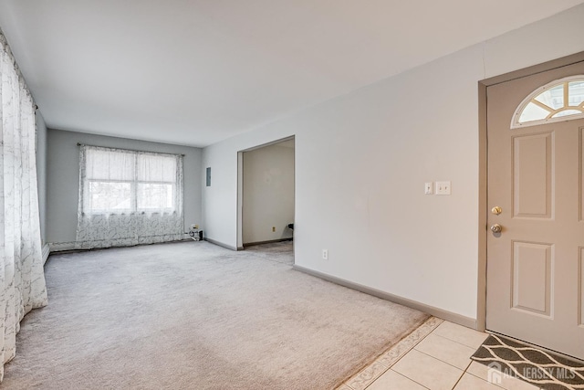 foyer with a baseboard radiator, light colored carpet, baseboards, and light tile patterned floors