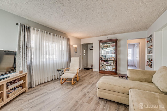 living room featuring a textured ceiling, baseboards, and wood finished floors