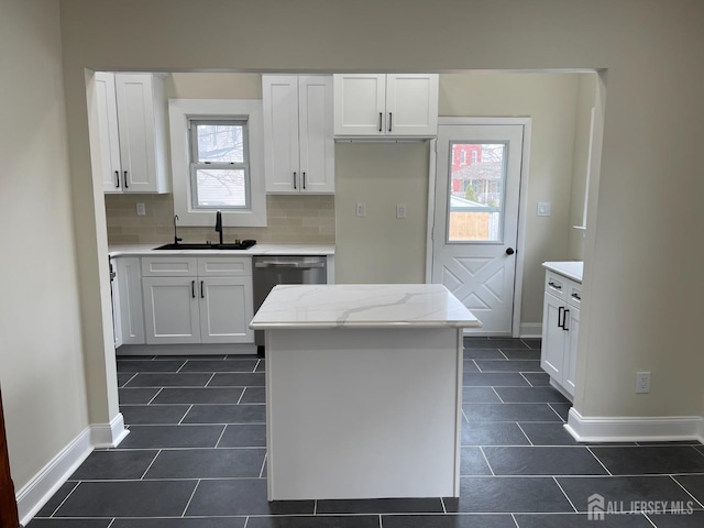 kitchen with a center island, a sink, dark tile patterned flooring, dishwasher, and white cabinetry