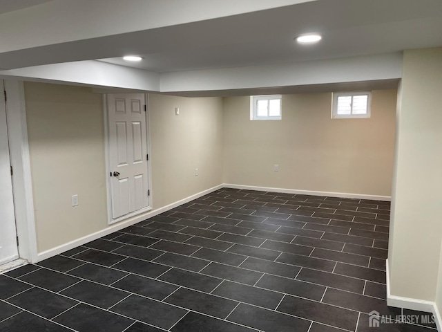below grade area with recessed lighting, baseboards, and dark tile patterned flooring