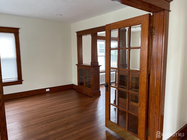 spare room featuring plenty of natural light, baseboards, and dark wood-style flooring