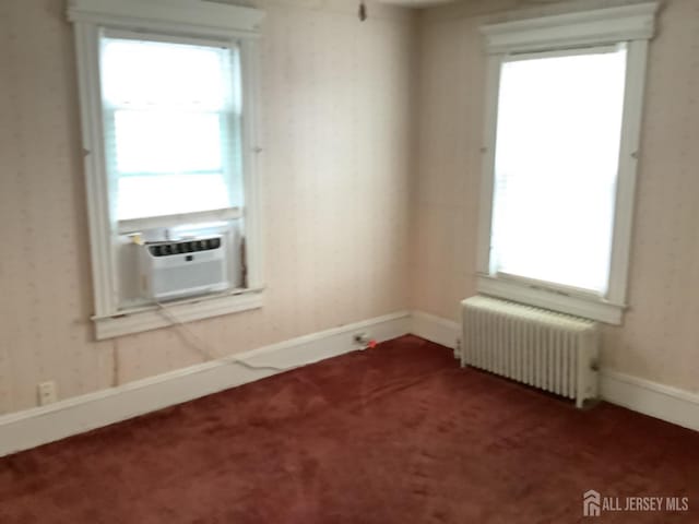 carpeted empty room with baseboards, a healthy amount of sunlight, radiator heating unit, and wallpapered walls