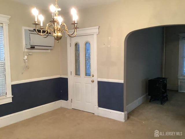 interior space with arched walkways, a wall unit AC, carpet flooring, a wood stove, and an inviting chandelier