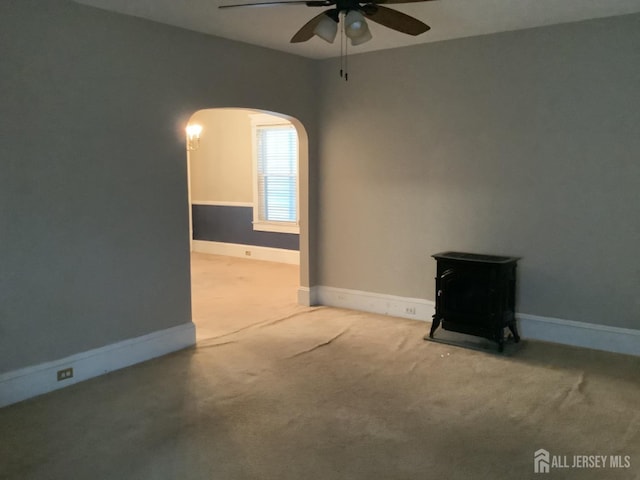 unfurnished room featuring arched walkways, carpet, a ceiling fan, and baseboards