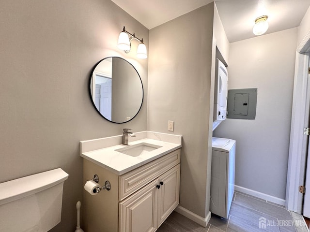 bathroom with stacked washer and dryer, vanity, electric panel, toilet, and baseboards