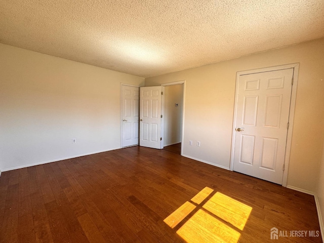 unfurnished bedroom with baseboards, wood finished floors, and a textured ceiling