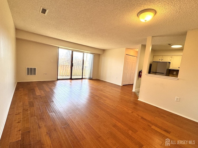 unfurnished living room featuring baseboards, dark wood finished floors, and visible vents