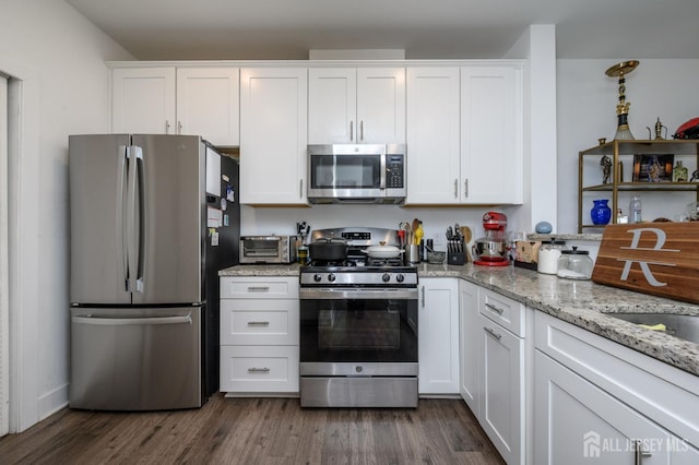kitchen featuring dark wood-style floors, white cabinetry, light stone counters, and appliances with stainless steel finishes