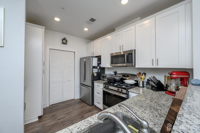 kitchen with stainless steel appliances, visible vents, white cabinetry, and dark wood-style floors