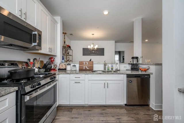 kitchen with a sink, dark wood-style flooring, a chandelier, white cabinetry, and stainless steel appliances