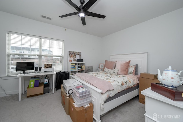 bedroom featuring visible vents, ceiling fan, radiator heating unit, and light carpet