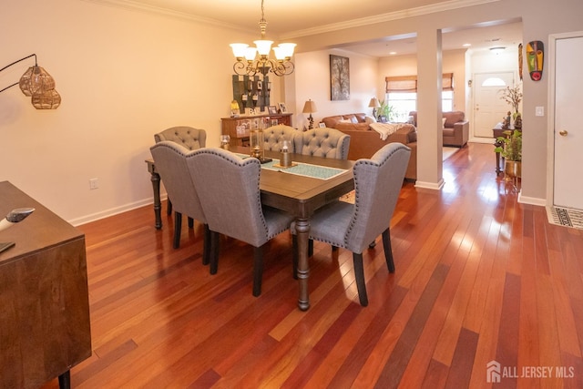 dining area featuring hardwood / wood-style flooring, a notable chandelier, baseboards, and crown molding