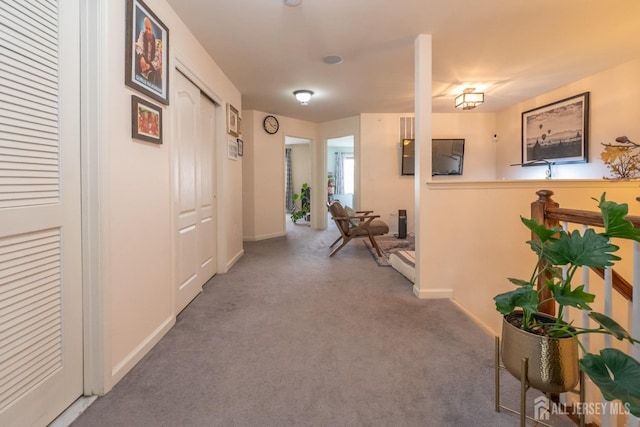 hall featuring baseboards and carpet flooring