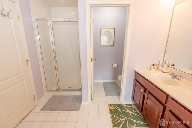 bathroom with toilet, vanity, baseboards, a shower stall, and tile patterned floors