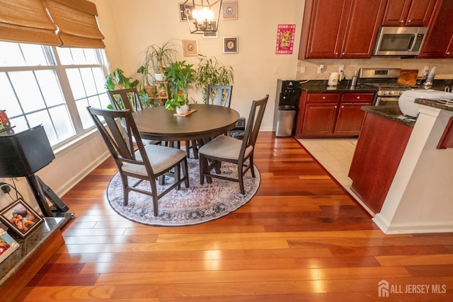 dining space with light wood finished floors, baseboards, and an inviting chandelier