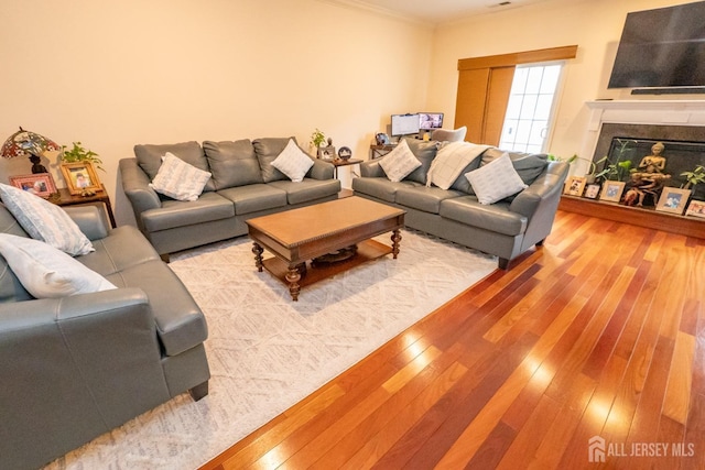 living area with hardwood / wood-style flooring, crown molding, and a high end fireplace