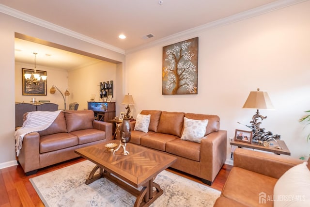 living area with visible vents, baseboards, ornamental molding, wood finished floors, and an inviting chandelier