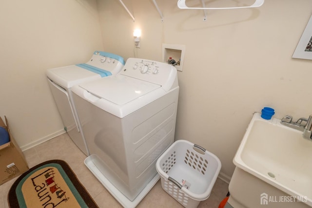 washroom with laundry area, washing machine and dryer, a sink, and baseboards