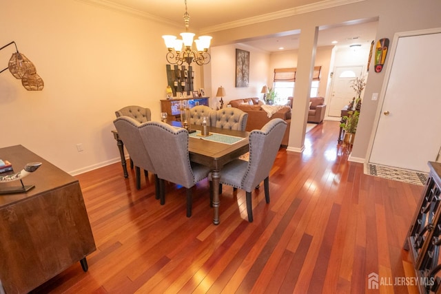 dining room with wood-type flooring, crown molding, baseboards, and an inviting chandelier