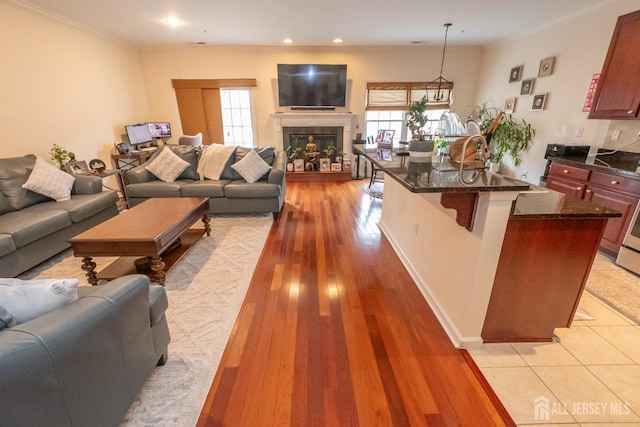 kitchen with a tiled fireplace, an island with sink, a breakfast bar area, open floor plan, and light wood-type flooring