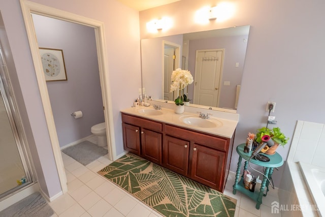 bathroom featuring a relaxing tiled tub, tile patterned flooring, a sink, and toilet