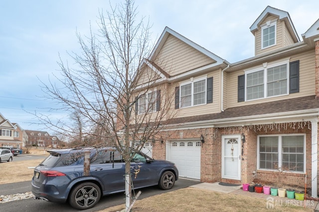 view of property featuring driveway, brick siding, an attached garage, and a shingled roof