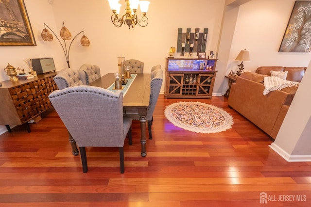 dining space with baseboards, a chandelier, and wood finished floors