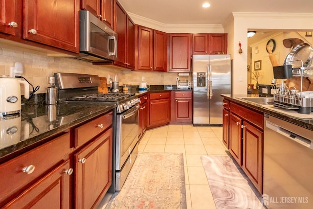 kitchen with light tile patterned floors, dark brown cabinets, appliances with stainless steel finishes, backsplash, and crown molding