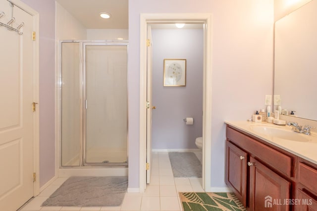 bathroom featuring toilet, a shower stall, vanity, baseboards, and tile patterned floors