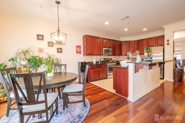 kitchen with crown molding, dark countertops, visible vents, appliances with stainless steel finishes, and light wood-style floors