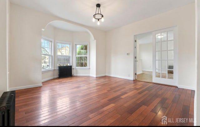 5 Warren St, Jamesburg, NJ 08831 - unfurnished living room with radiator heating unit, arched walkways, and wood-type flooring